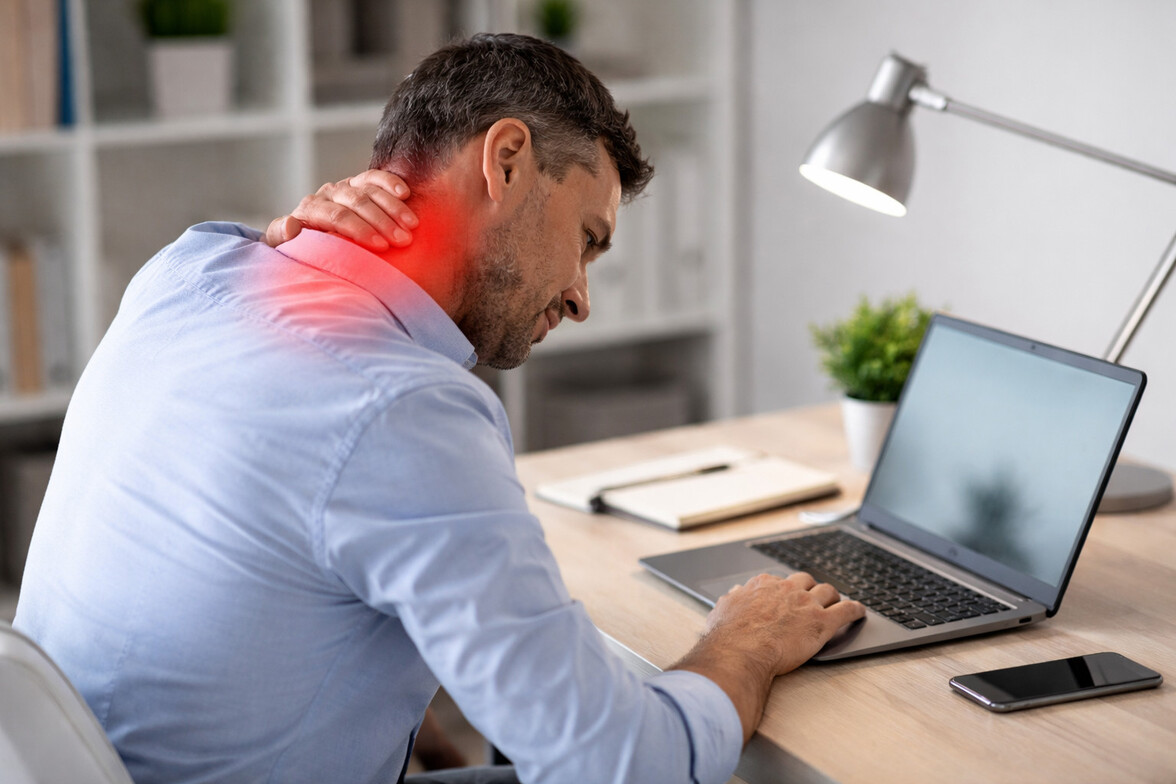 Adult working at a desk with subtle red highlight at base of neck