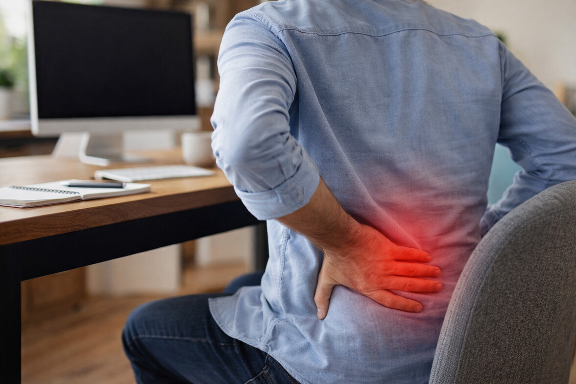 Adult sitting at desk with subtle red highlight on lower back