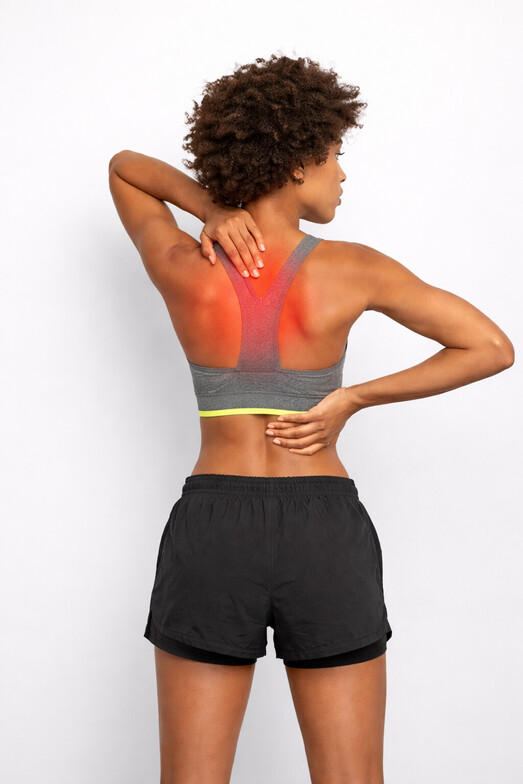 Person holding upper back between shoulder blades with subtle red indicator showing upper back pain in Olathe